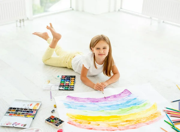 Menina desenha deitado no chãopequena menina alegre desenha deitado no chão — Fotografia de Stock