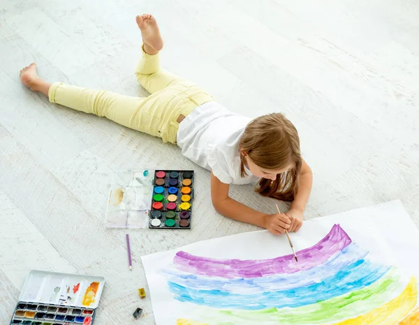 Menina desenha deitado no chãopequena menina alegre desenha deitado no chão — Fotografia de Stock