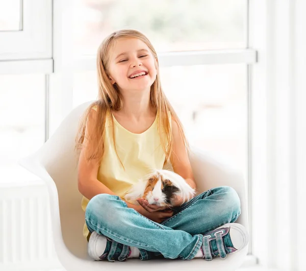 Smiling kid girl holding cute guinea pig — Stock Photo, Image