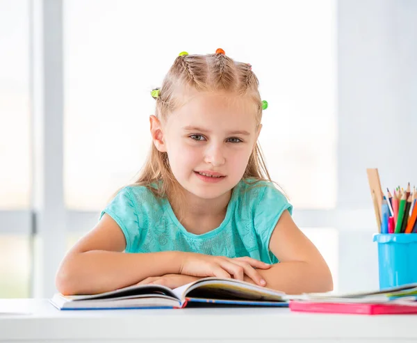 Söt skolflicka sitter med öppen bok — Stockfoto