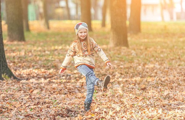 Menina chutando folhas de outono — Fotografia de Stock