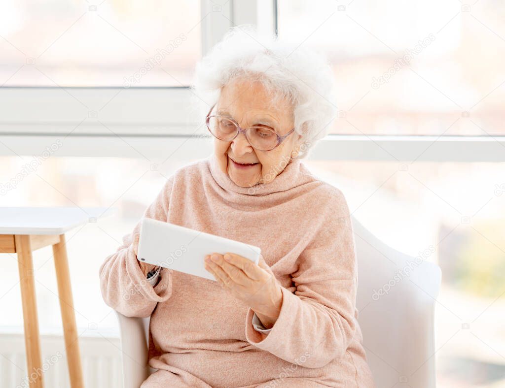 Aged woman in glasses with tablet