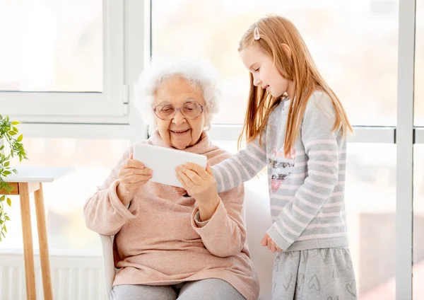 Niña enseñando mujer anciana —  Fotos de Stock