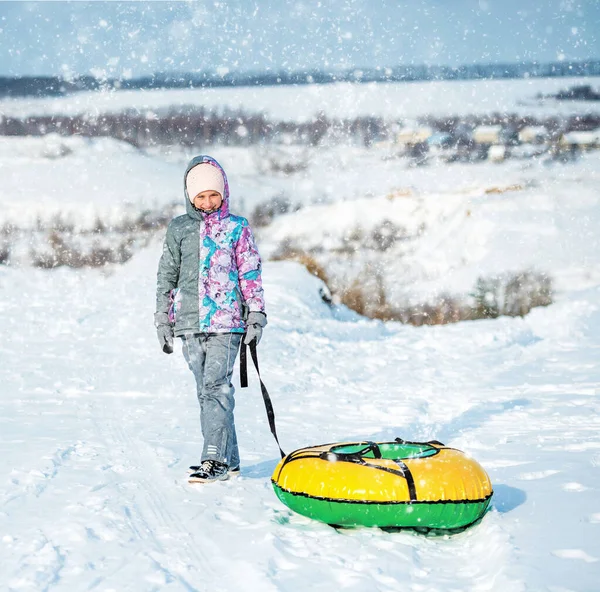 Meisje in ski kleding sleept buizen sneeuw op de heuvel — Stockfoto