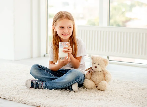 Kız bir bardak sütle oturur. — Stok fotoğraf
