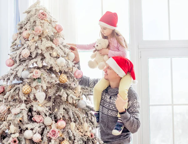 Отец держит дочь возле рождественской елки — стоковое фото