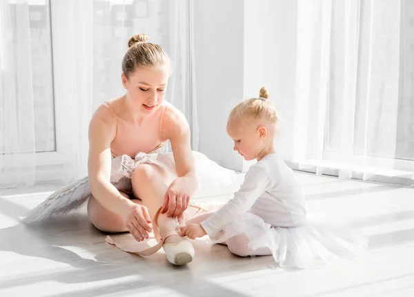 Маленьку дівчинку вчать зав'язувати взуття для балету — стокове фото