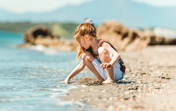 Little girl builds a tower of sand — Stock Photo, Image