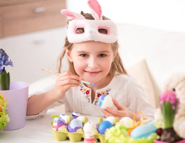 Çocuk Paskalya için yumurta boyuyor.