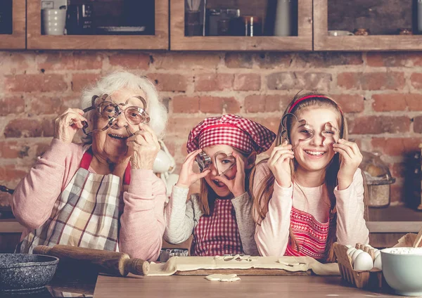 Avó com netas olhando para a câmera através de cortadores de biscoitos — Fotografia de Stock