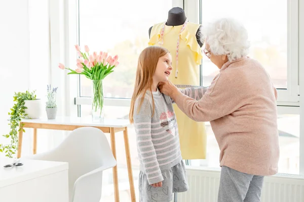 Woman taking measures of granddaughter — ストック写真