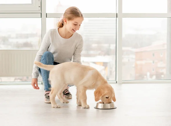 Gelukkig meisje naast eten puppy — Stockfoto
