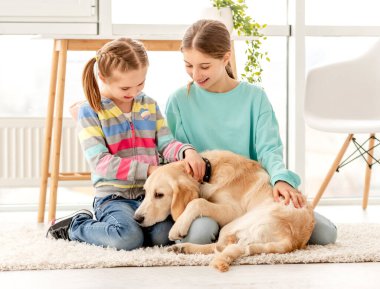 Mutlu kız kardeşler sevimli köpekleri kucaklıyor.