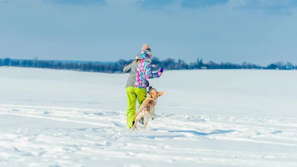 Ragazza che corre nella neve con il cane — Foto Stock