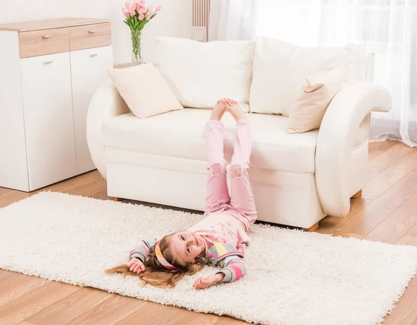 Usmívající se dívka se protahuje v obývacím pokoji — Stock fotografie