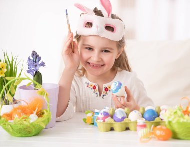 Maskeli yumurtaları boyayan kız