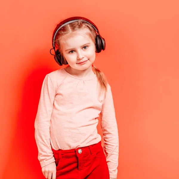 Petite fille dans les écouteurs sur fond rose — Photo