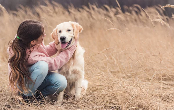 Mutlu kız okşayan genç köpek — Stok fotoğraf