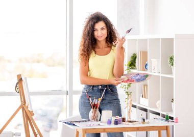 Sanat teçhizatıyla atölyedeki ressam