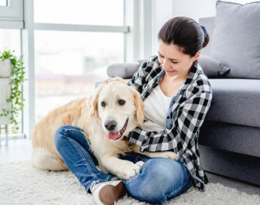 Güzel bir kadın sevimli bir köpeği kucaklıyor.