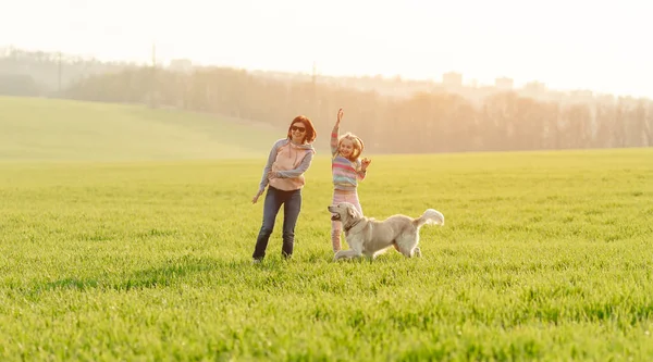 Kvinna och flicka leker med hund — Stockfoto