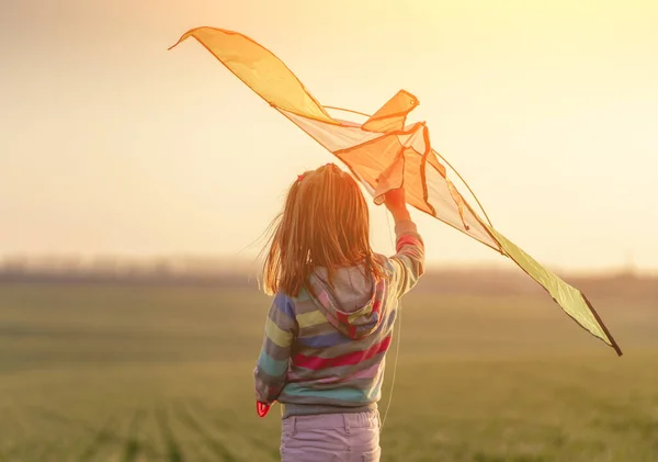 Niña sosteniendo cometa al atardecer — Foto de Stock