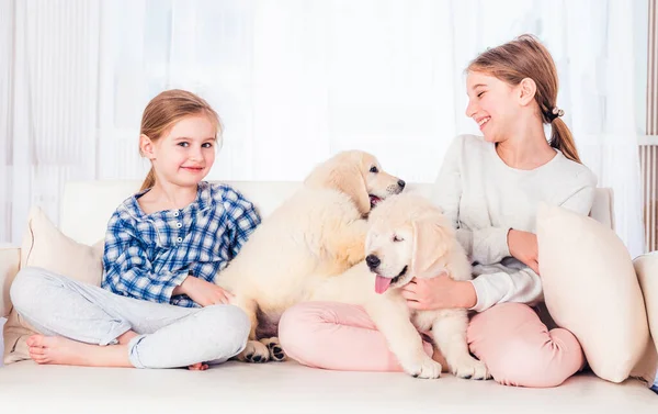 Gülümseyen kız kardeşler köpek yavrularıyla oturuyor — Stok fotoğraf