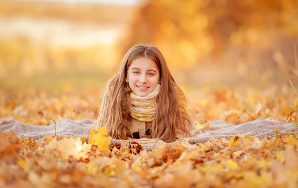 Menina sentada em folhas amarelas — Fotografia de Stock