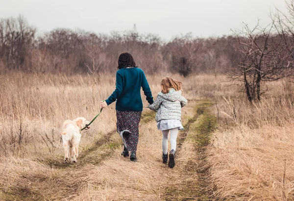 Mother and daughter walking dog — Stock Photo, Image