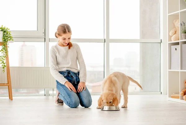Ragazza felice accanto a mangiare cucciolo — Foto Stock