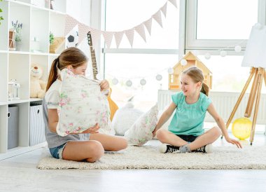 Yastıklarla savaşan gülümseyen kızlar