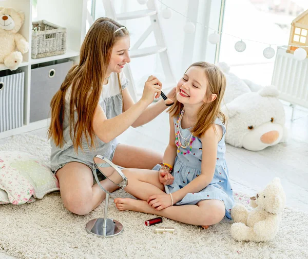 Crianças sorridentes aplicando maquiagem cosméticos — Fotografia de Stock