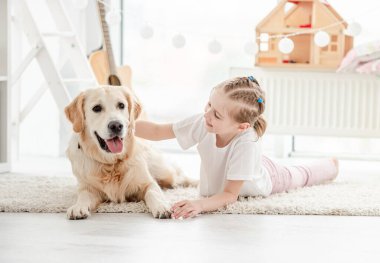 Gülümseyen küçük kız tapılası köpeği okşuyor