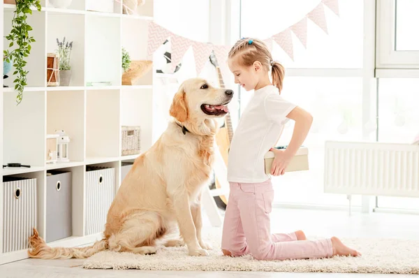 Klein meisje presenteren geschenk aan hond — Stockfoto