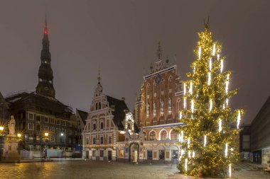 Noel ağacı, Riga, Letonya ışıklı siyah nokta ev ve St Peter Kilisesi karşı koyu mavi gökyüzü ile.