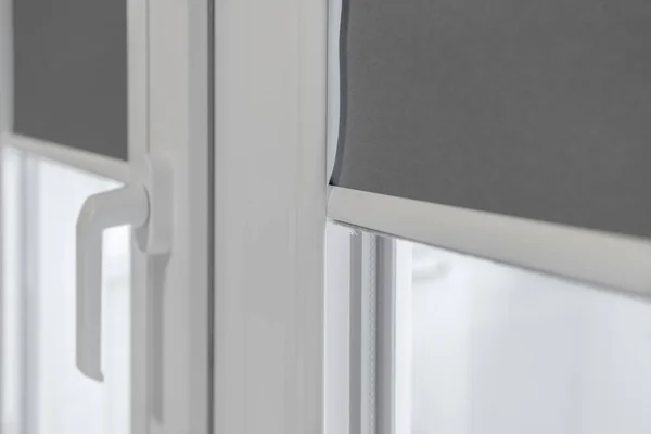 A fragment of a plastic window. PVC window with lowered roll-up blinds