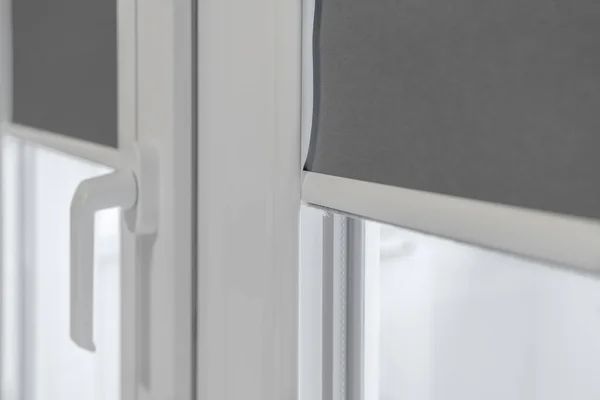 Fragment eines Kunststofffensters. PVC-Fenster mit abgesenkten Rollos lizenzfreie Stockbilder
