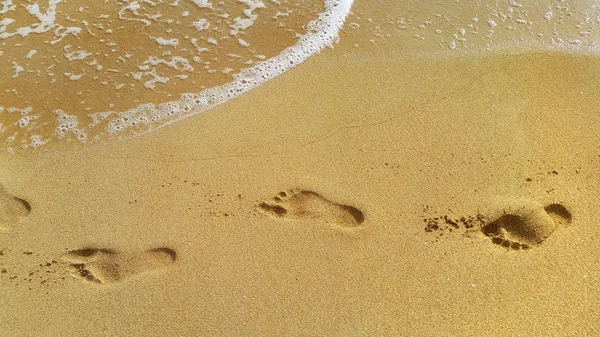 Agua de mar y huellas en la arena de la playa — Foto de Stock