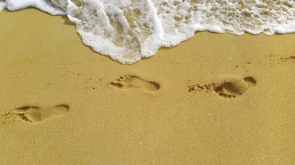 Espuma marina y huellas en la arena de la playa — Foto de Stock