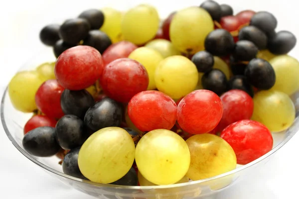 Surtido brillante sabrosas uvas maduras en un plato de vidrio — Foto de Stock