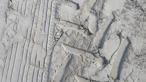 Песчаный фон с отпечатками колес и следов — стоковое фото