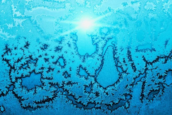 Mooie ijs patroon en fel zonlicht op winter glas — Stockfoto