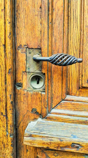 Vintage yellow wooden door with decorative handle and keyhole — Stock Photo, Image