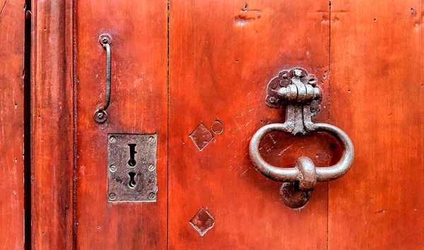 Vintage red wooden door with metallic doorhandle and keyholes — Stock Photo, Image