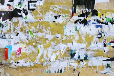 Dirty street yellow wall with old torn and peeling poster paper 
