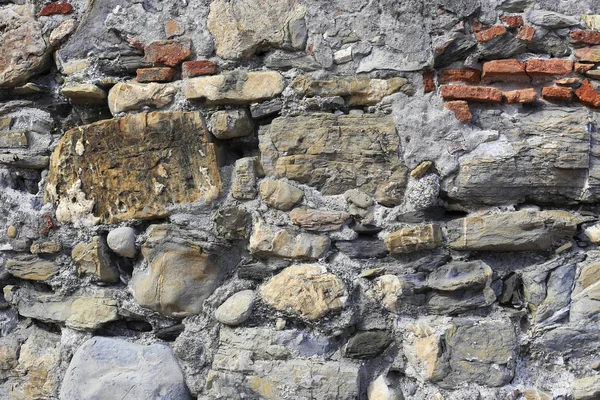 Oude muur van stenen van verschillende vormen en rode bakstenen — Stockfoto