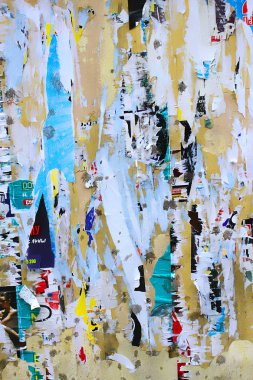 Dirty street yellow wall with old torn and peeling poster paper