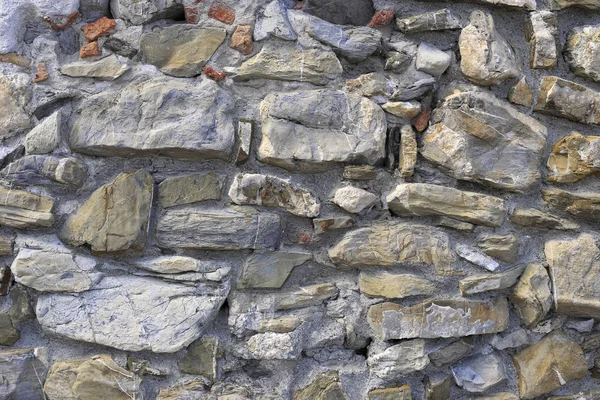 Parede muito antiga de pedras de várias formas e tijolos vermelhos — Fotografia de Stock