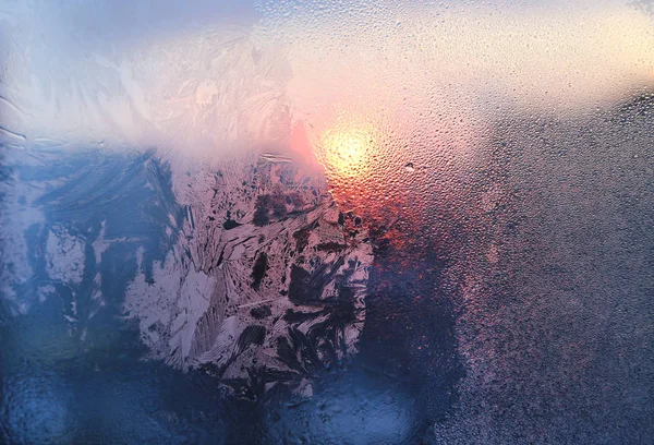 Patrón de hielo, gotas de agua y luz solar en una ventana de invierno congelada — Foto de Stock