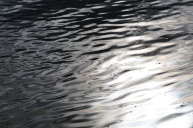 Dalgalı su yüzeyinde güneş parlıyor.